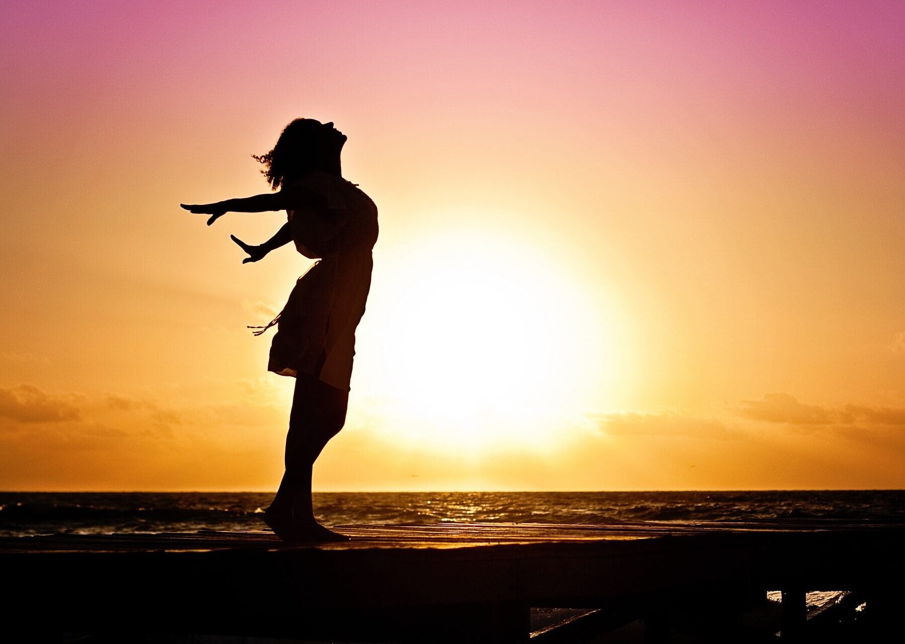 nainen auringonlaskussa rannalla
